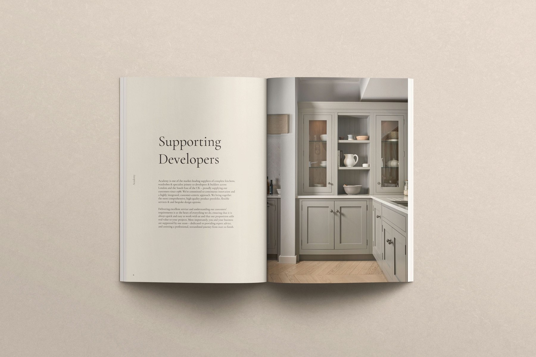 Academy Kitchens brochure open at the Supporting Developers spread with a pale green shaker kitchen, print design by HDEY
