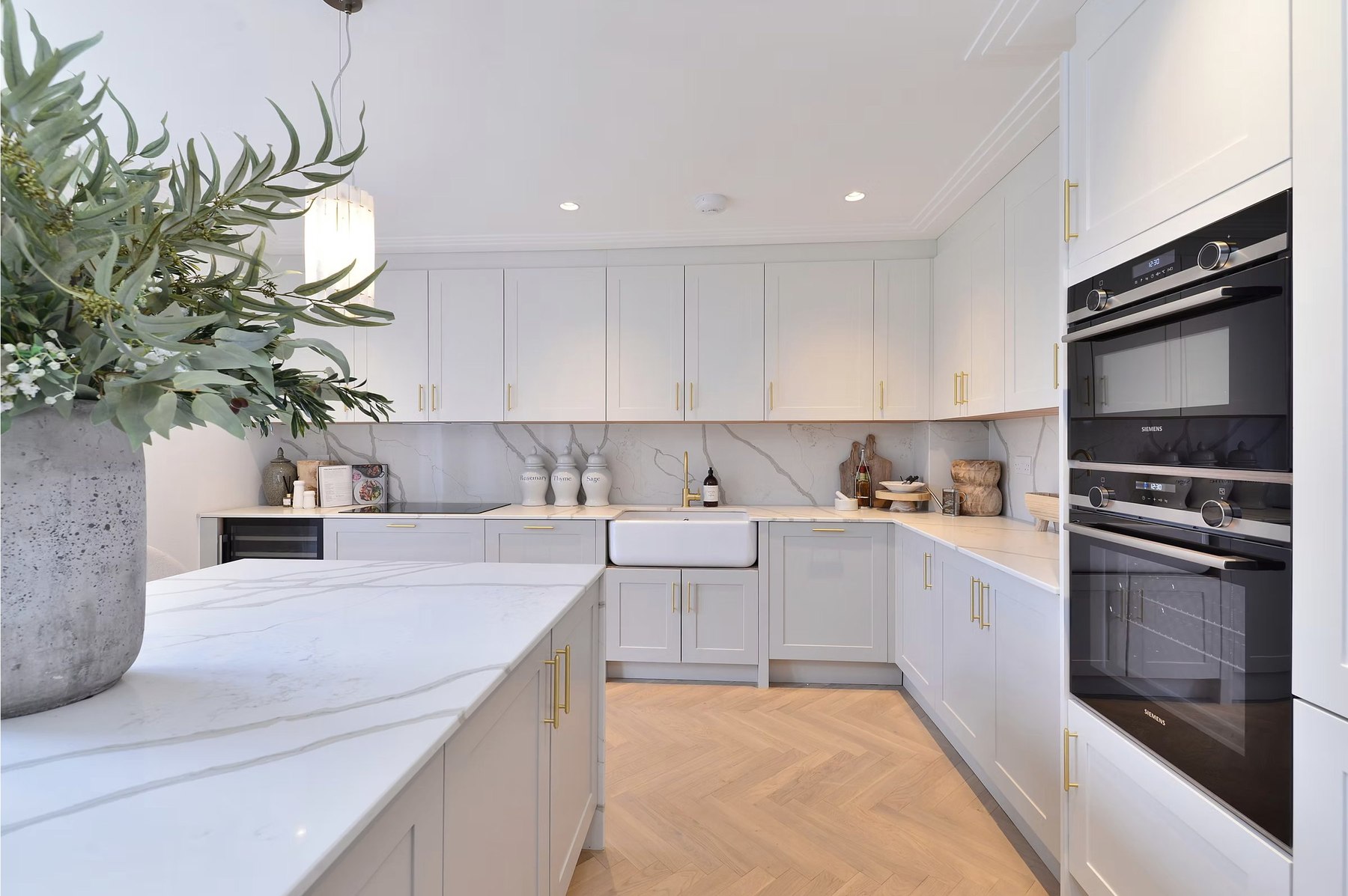 Alfold Gardens completed kitchen with marble countertops, island layout and gold hardware, Surrey — interior design by HDEY