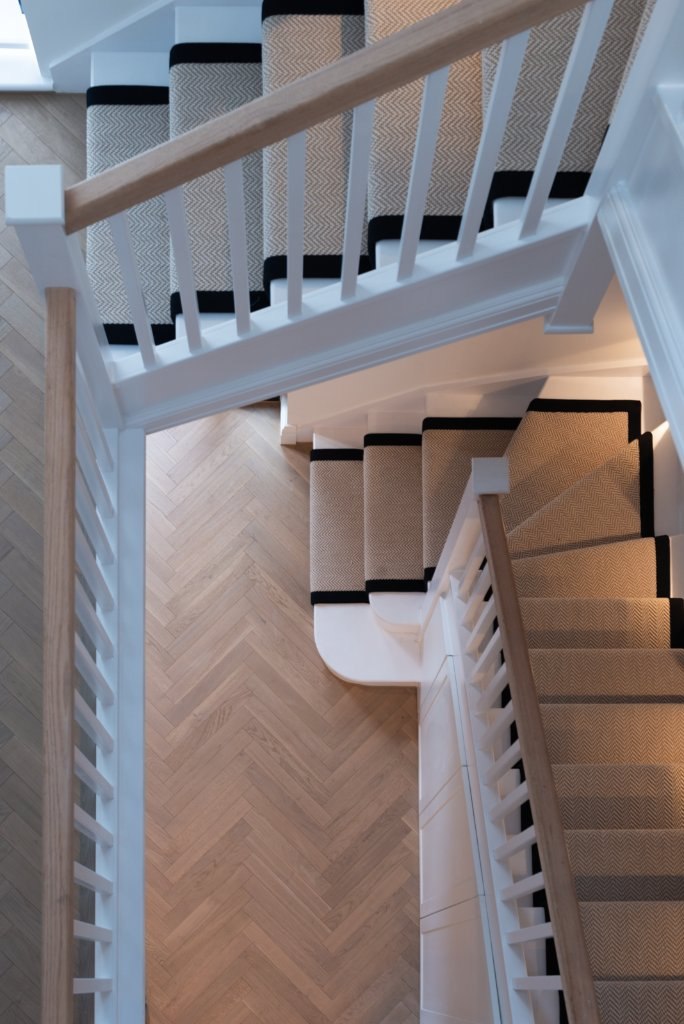 Alfold Gardens staircase detail with herringbone flooring and bannister, Surrey — interior design by HDEY