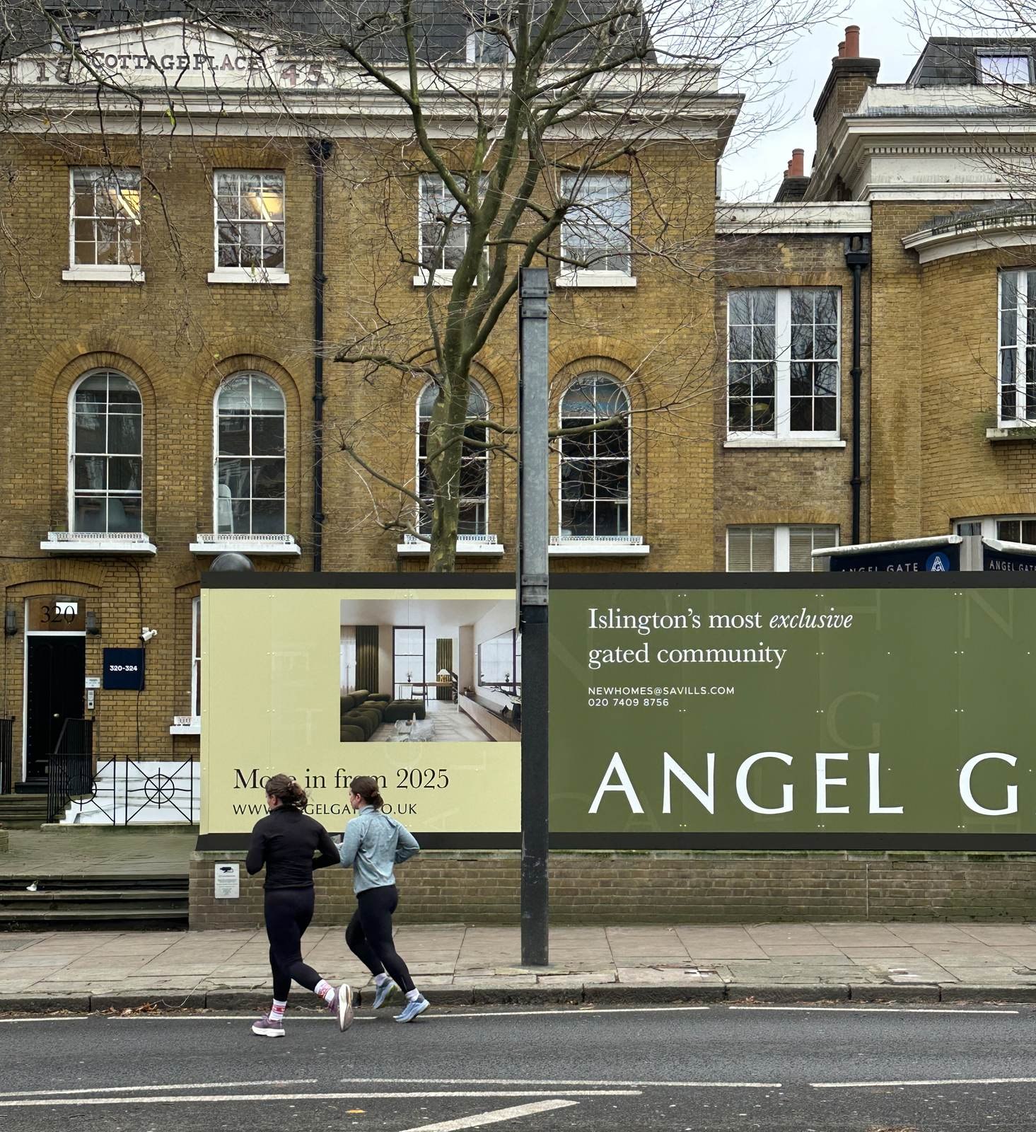 Angel Village site hoarding on City Road, Islington, showing apartment interiors — by HDEY