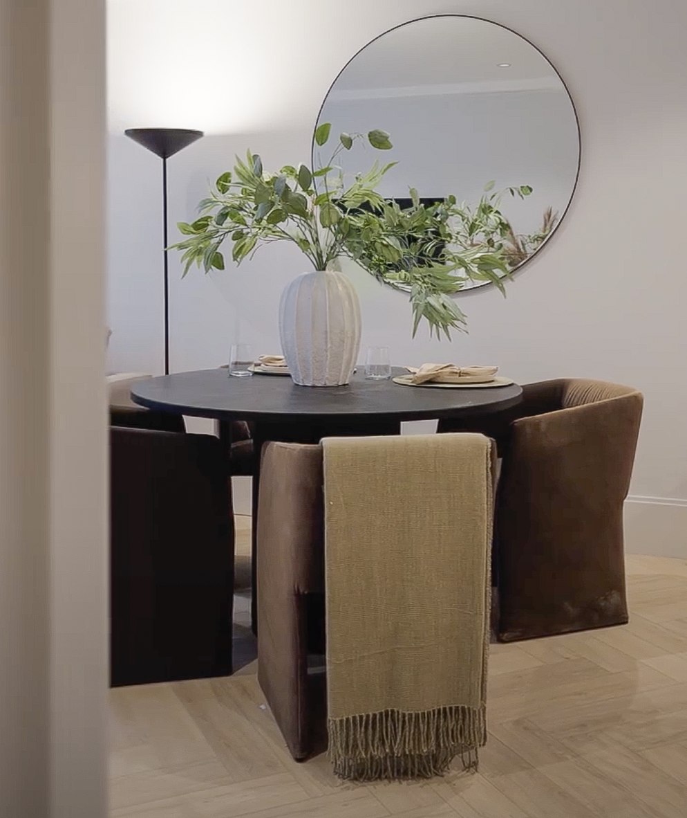 Ealing Broadway show home dining area with a round black table, brown velvet chairs and a circular mirror, West Ealing W13 — styling by HDEY