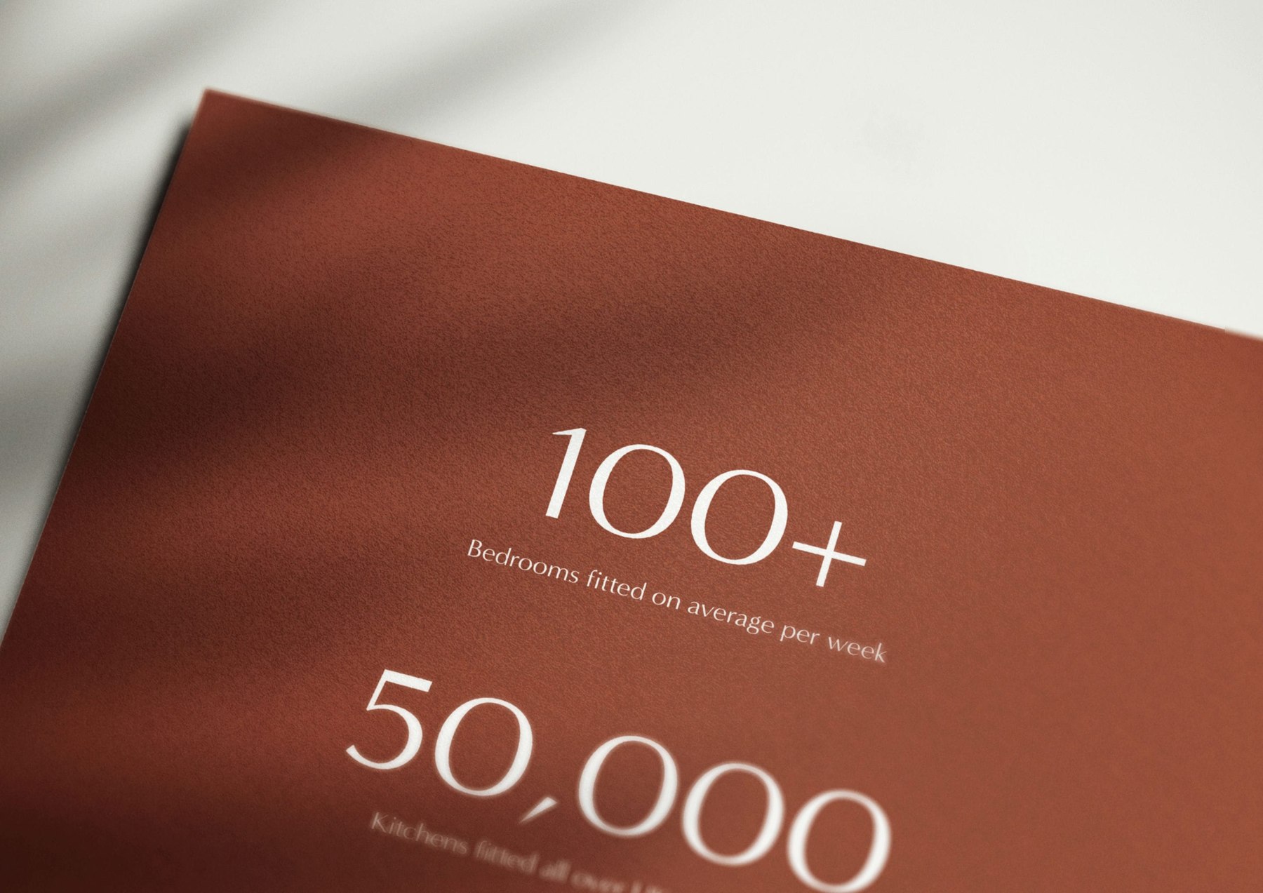 Fieldhouse brochure spread in terracotta setting out the numbers — 100+ bedrooms fitted per week and 50,000 kitchens installed, print design by HDEY