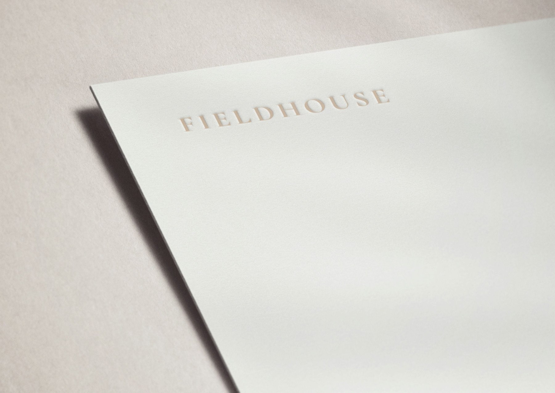 Fieldhouse letterhead with the logotype blind embossed in warm tone on off-white stock, brand identity by HDEY