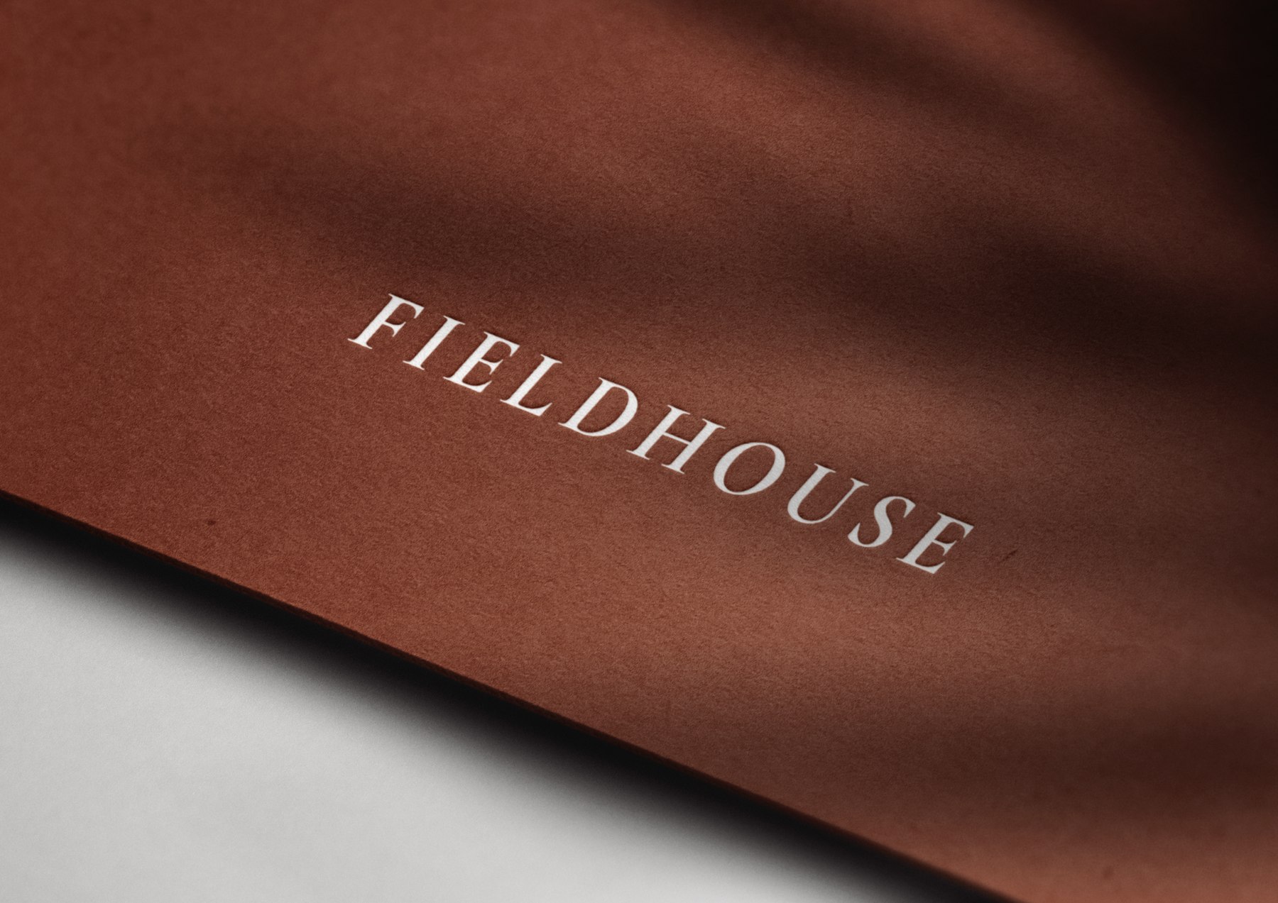 Fieldhouse logotype foiled in white on a terracotta stock, brand identity by HDEY