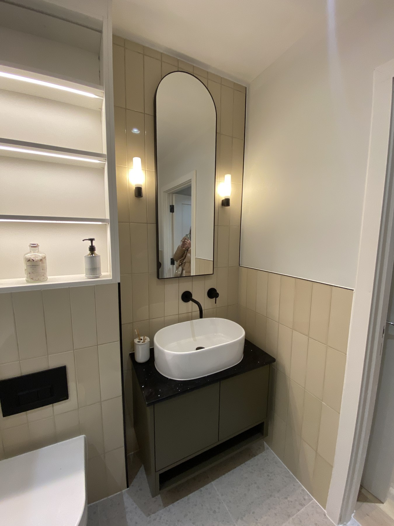 Fifty One bathroom as built, showing the stacked clay tiling, lit niche, dark vanity and arched mirror from the visual, Ealing