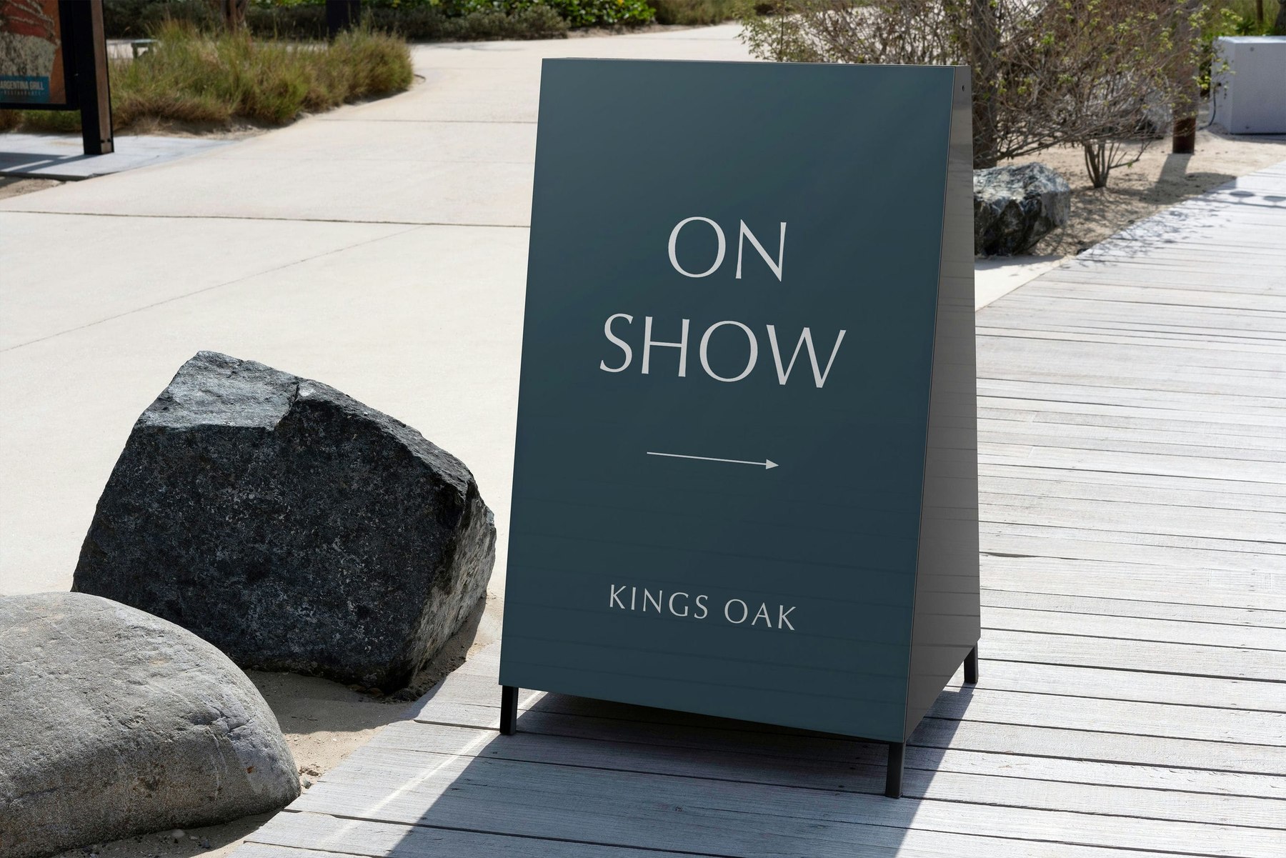 Kings Oak ON SHOW site board in petrol blue with a directional arrow and the logotype beneath, signage design by HDEY