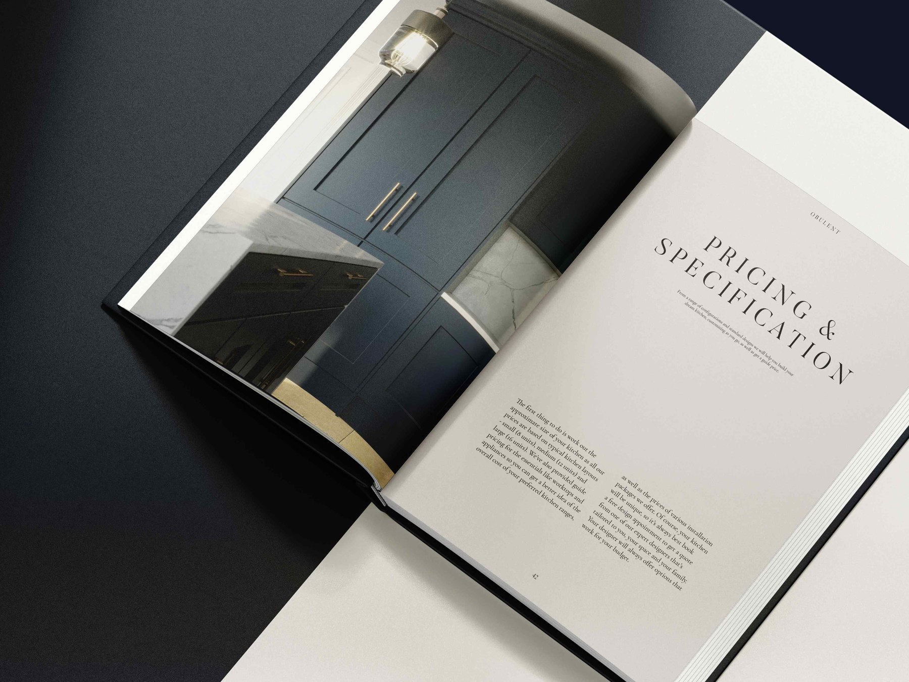 Obulent brochure open at the Pricing and Specification spread facing a navy shaker kitchen with brass detailing, print design by HDEY