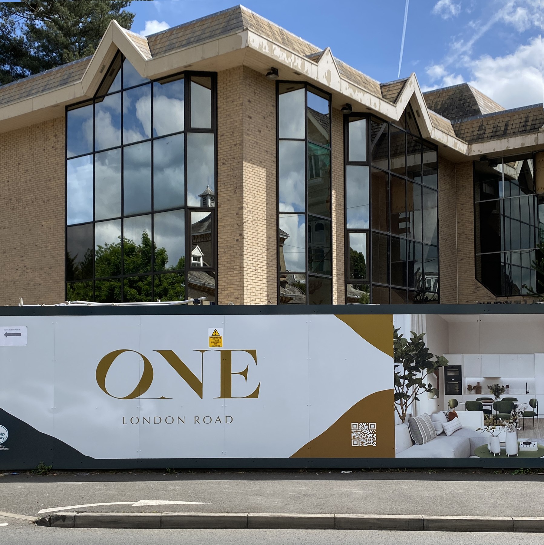 One London Road hoarding wrapped around the site in ochre, charcoal and white with the ONE mark, Upton, Slough — hoarding design by HDEY
