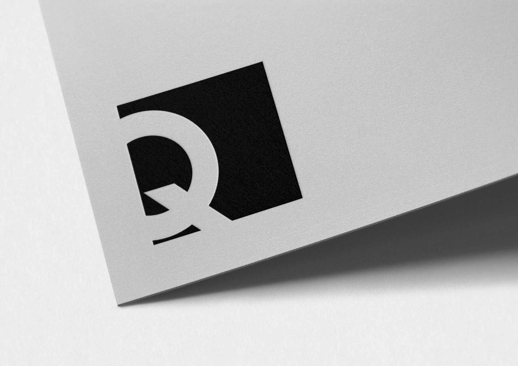Q Developments monogram debossed on grey stock — the existing Q mark