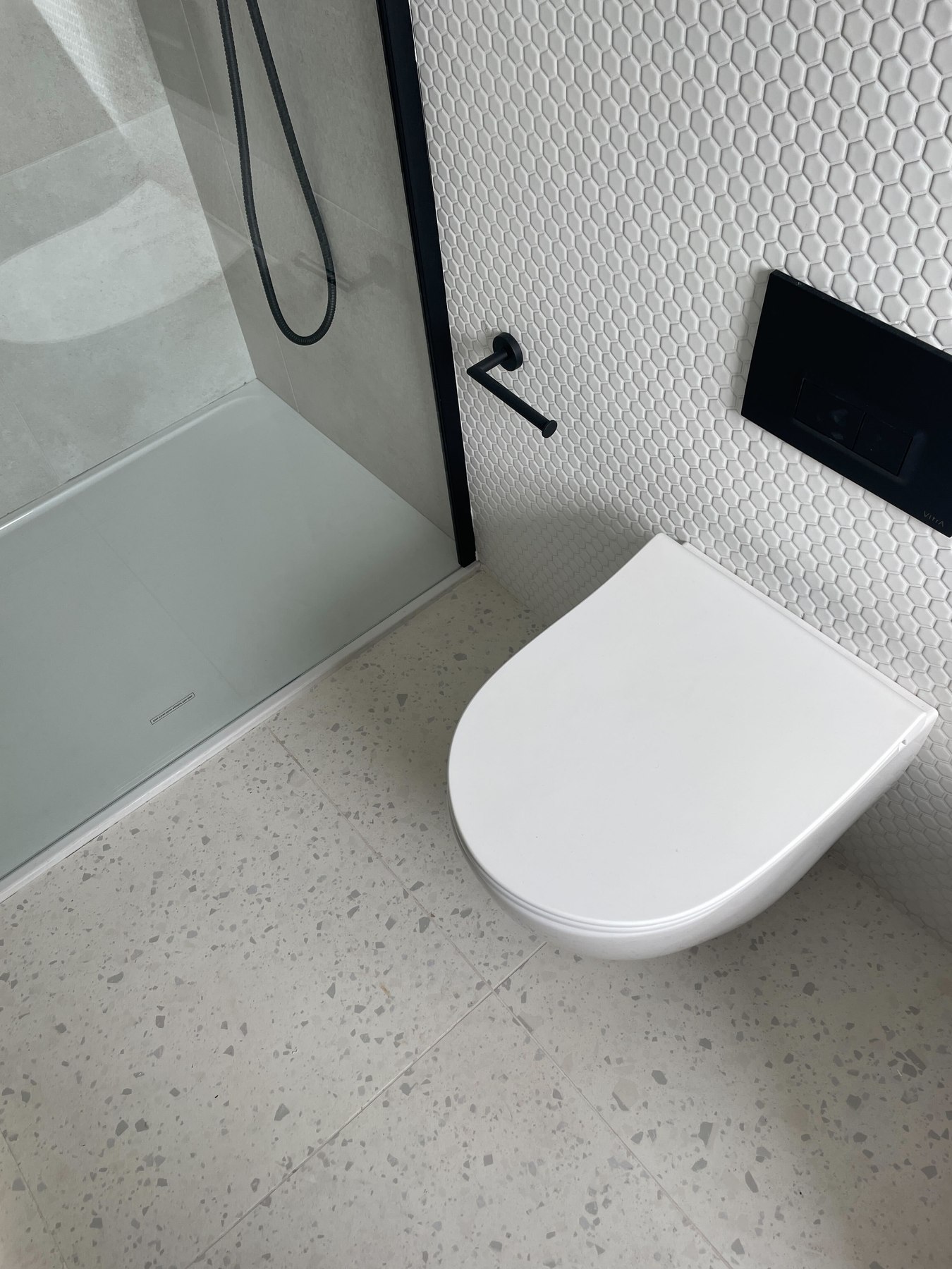 Q17 Lofts bathroom as built, showing the hexagonal mosaic, terrazzo floor and black fittings from the CGI, Walthamstow