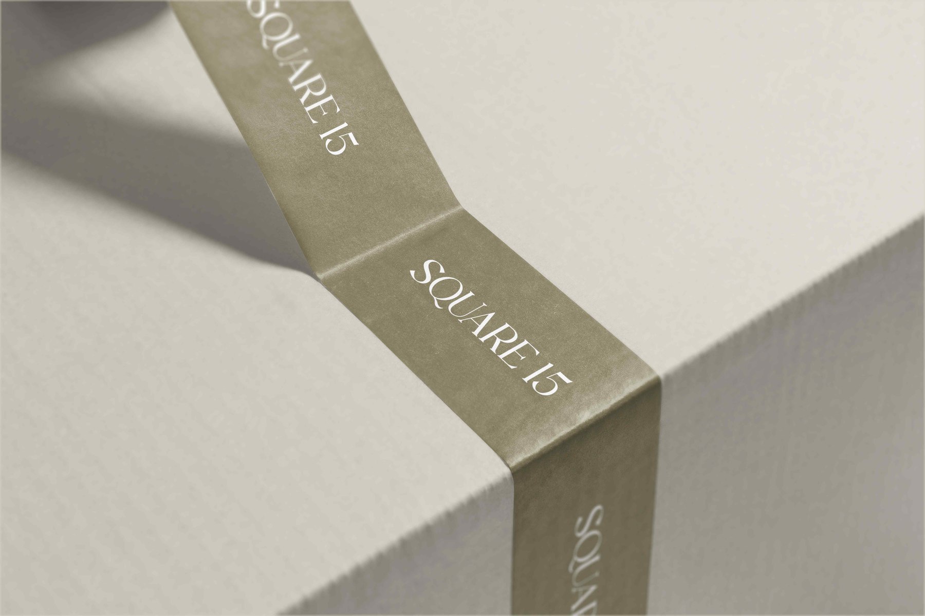 Square 15 branded packing tape in olive with the logotype repeated in white, sealing an off-white box, brand materials by HDEY