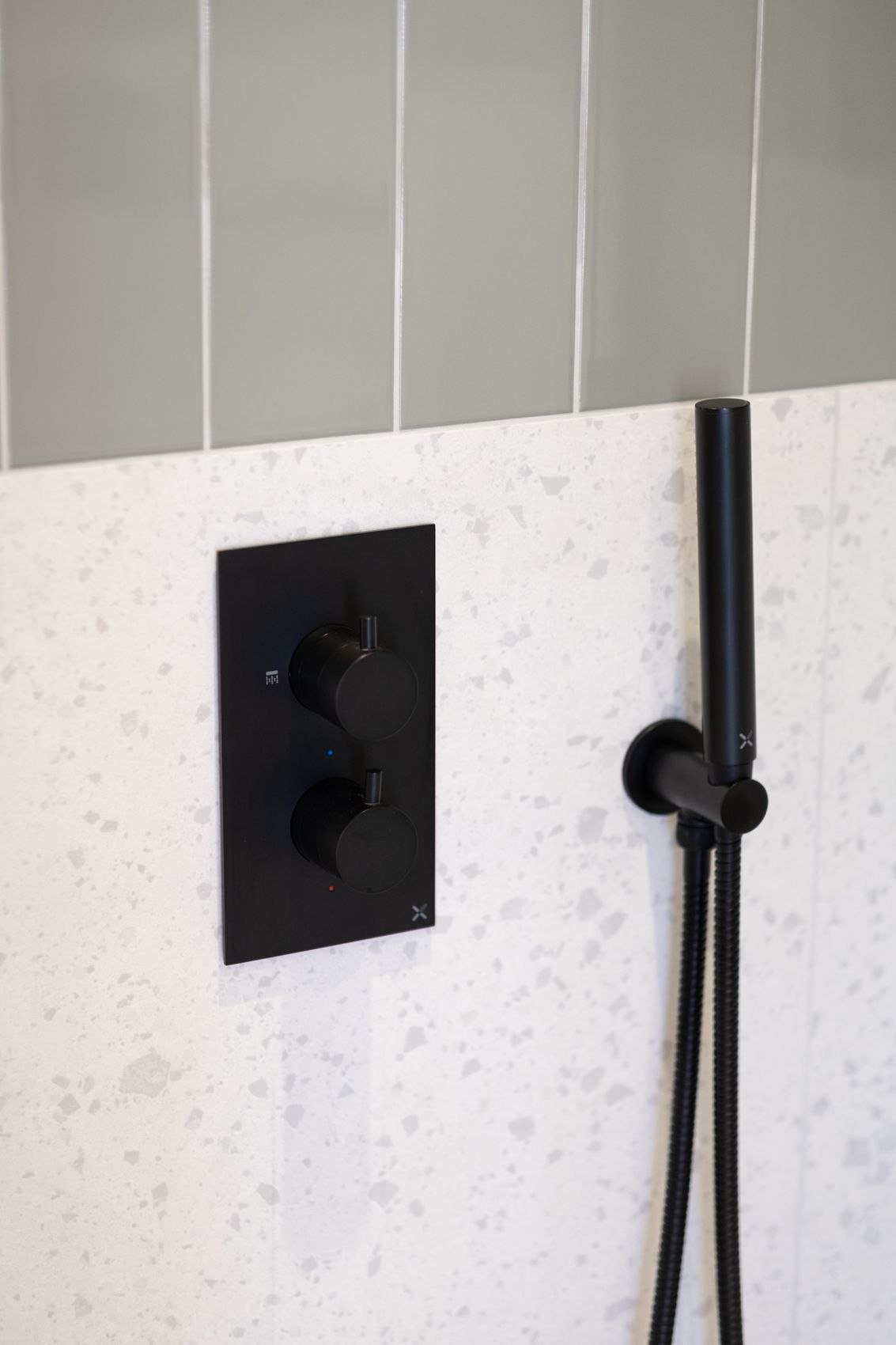 Streatley Road shower detail with black brassware on terrazzo tiling, London, specification by HDEY