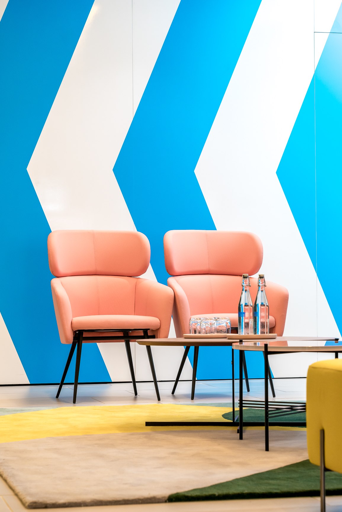 Twenty seating area with two coral armchairs against blue and white chevrons and a colour-block rug, London Bridge — styling by HDEY