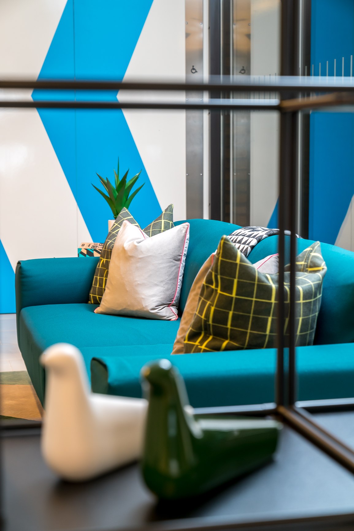 Twenty teal sofa with checked and geometric cushions against a blue chevron wall, London Bridge — styling by HDEY