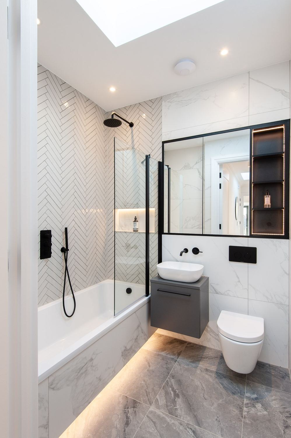 West Lodge bathroom with Calacatta marble, herringbone tiling and black-framed shower screen, Ealing — by HDEY