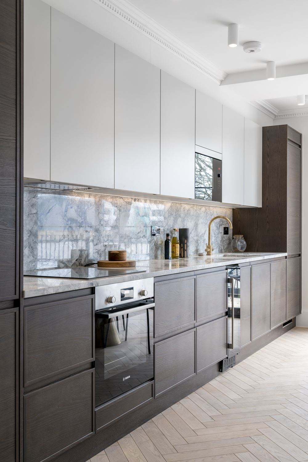 West Lodge galley kitchen with walnut units and marble splashback on herringbone flooring, Ealing — by HDEY