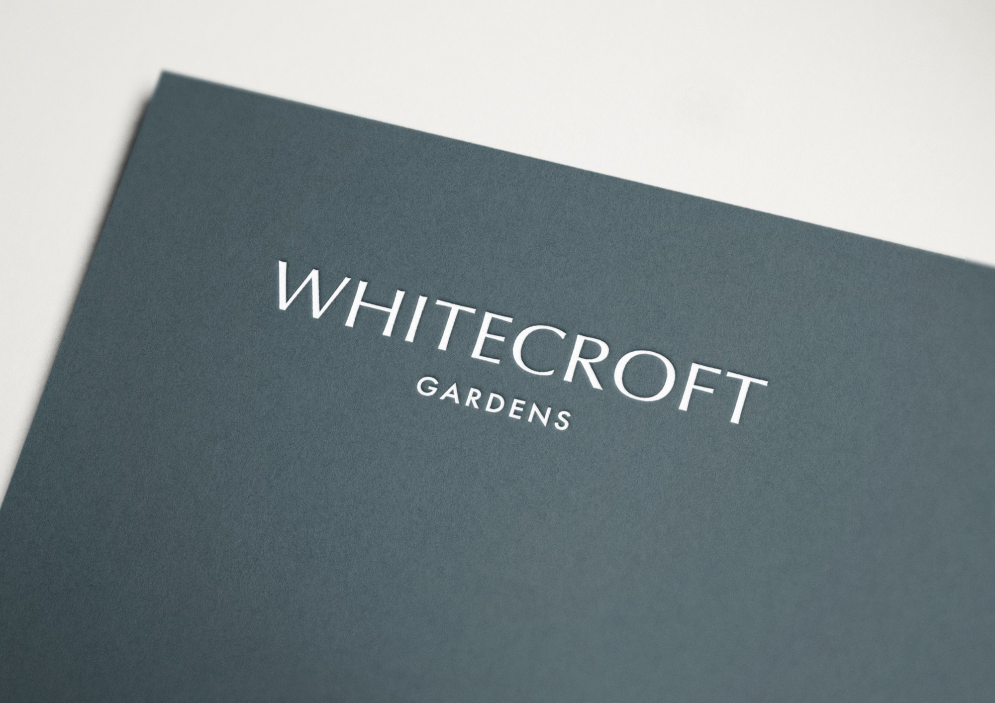 Whitecroft Gardens wordmark in white on a slate brochure cover, brand identity by HDEY