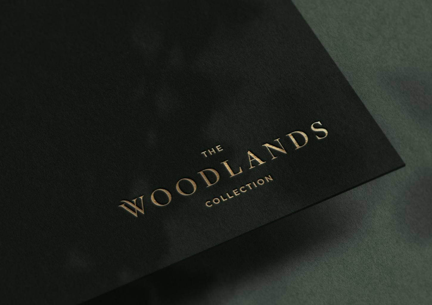 The Woodlands Collection logo foiled in gold on deep forest green — brand identity by HDEY